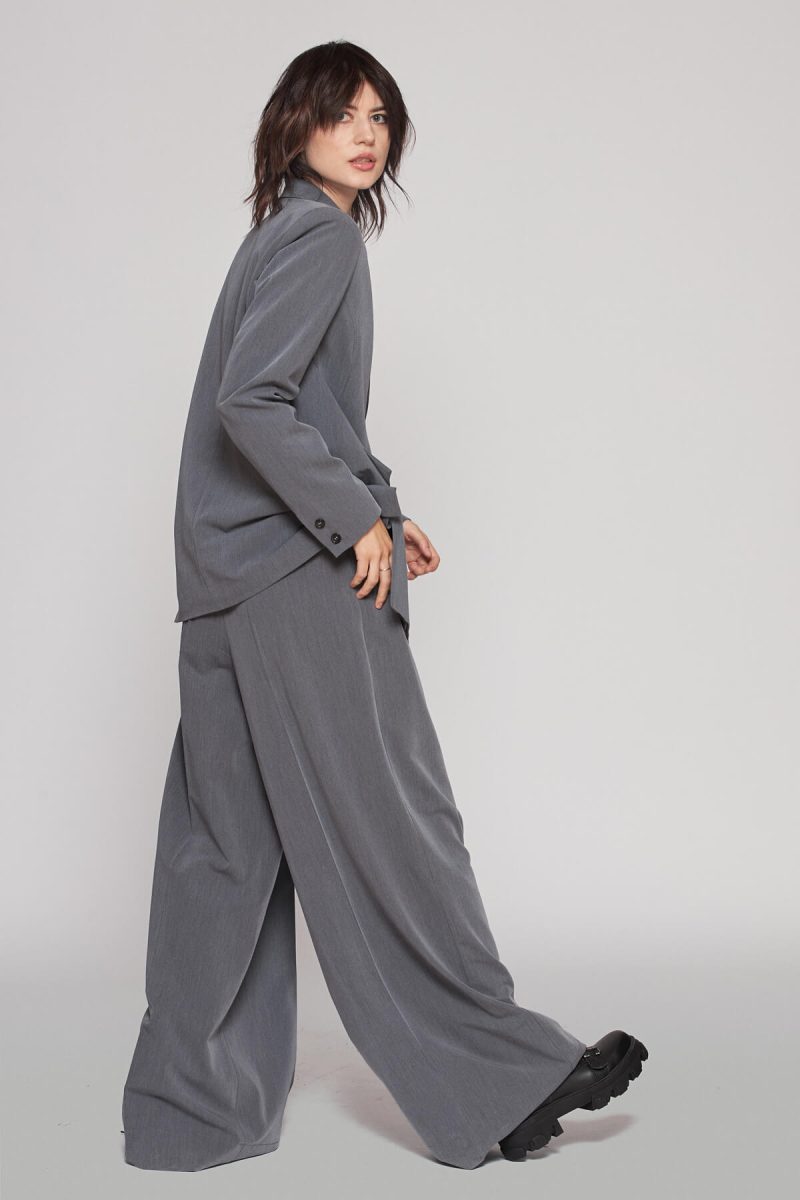 Oversized fine cut jacket with pockets symmetrically aligned, paired with wide leg pleated trousers to create an elegant ensemble.